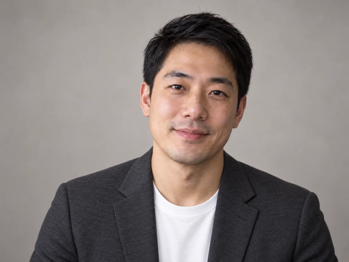 The same man in a blazer against a neutral studio background