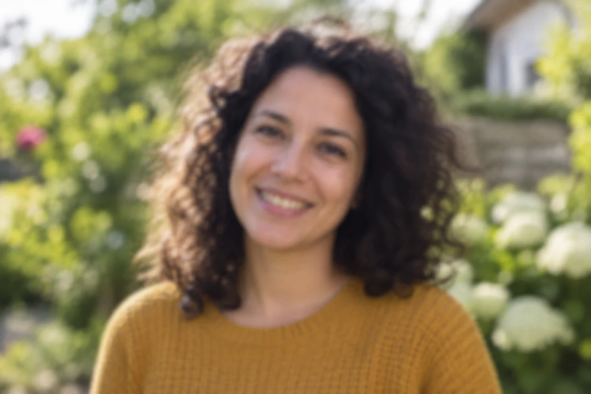 A curly-haired woman in an ochre sweater outdoors, before editing