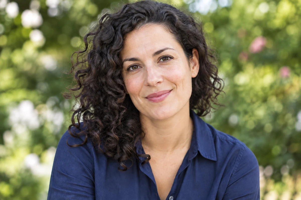 A woman with curly hair and a navy shirt in a garden, after removing the watermark