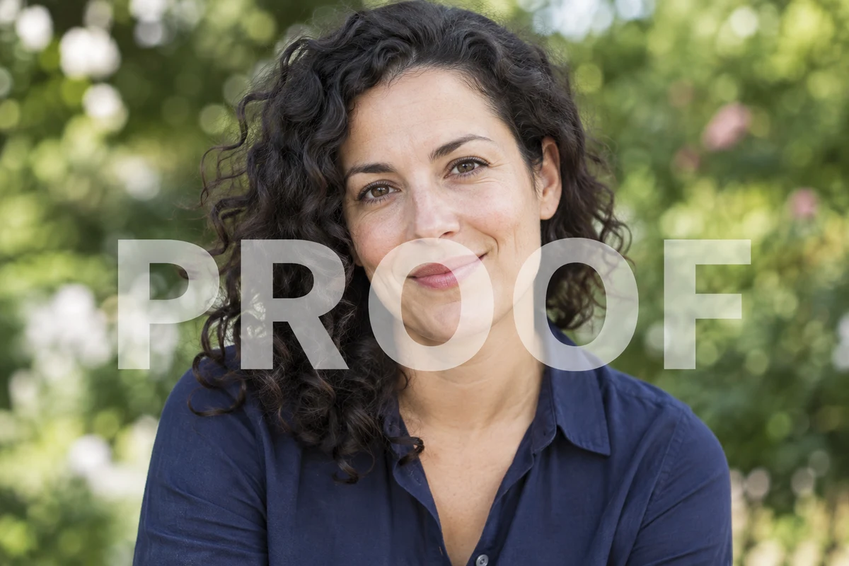 A woman with curly hair and a navy shirt in a garden, with an overlaid watermark